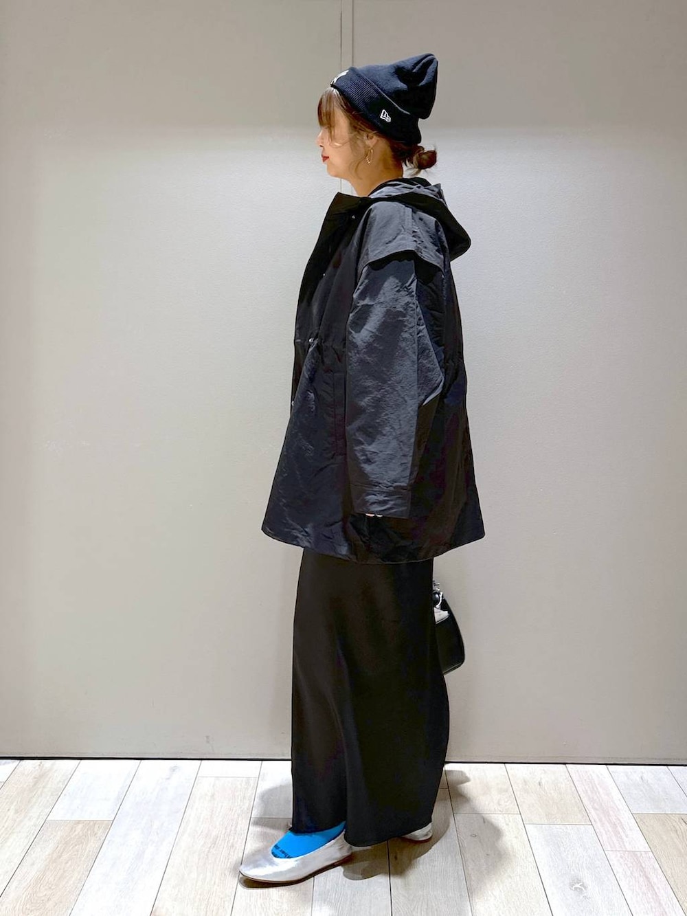 グレー系のチュニック、グレー系のパンプス、ブラック系のスカートを着用したレディースの春コーディネートの4枚目の写真