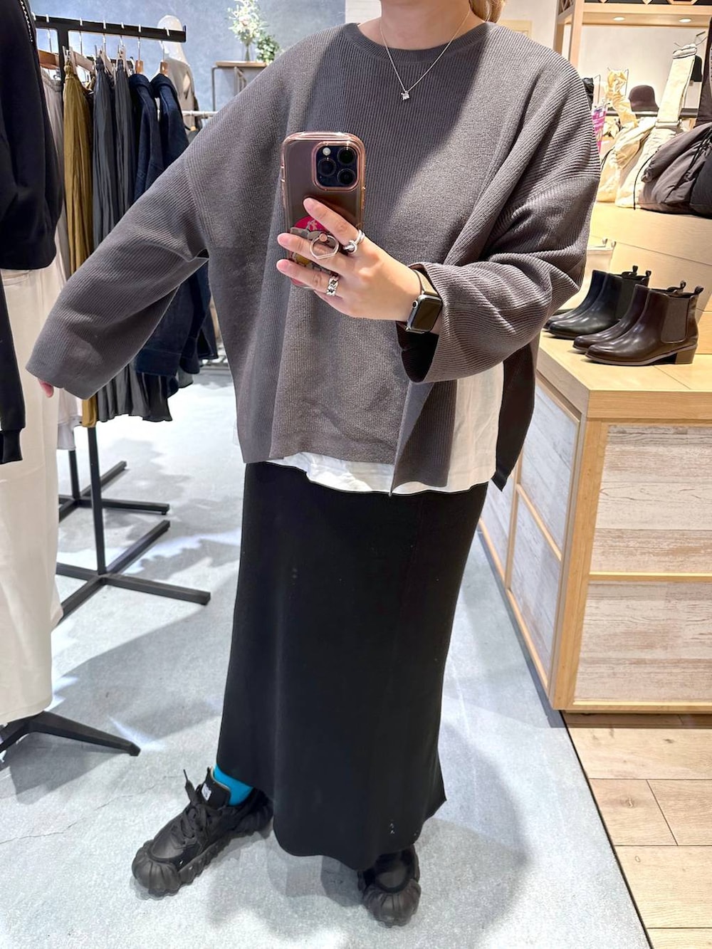 ホワイト系のTシャツ/カットソー、グレー系のニット/セーター、ブラック系のスカートを着用したレディースの秋コーディネートの2枚目の写真