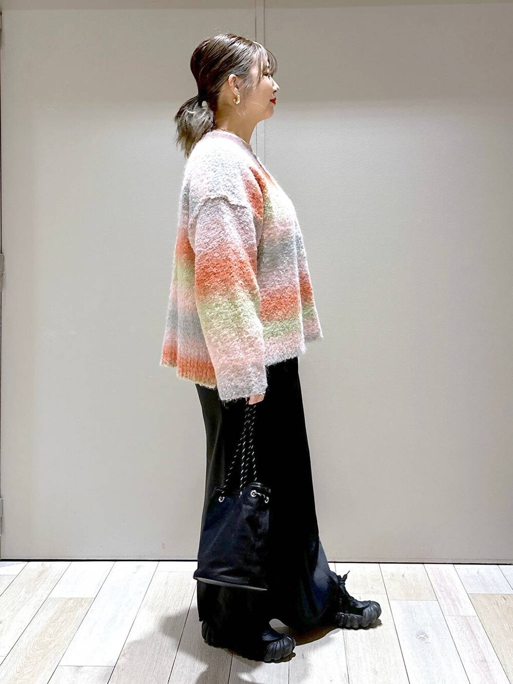 ブラック系のスカート、オレンジ系のニット/セーターを着用したレディースの秋コーディネートの2枚目の写真