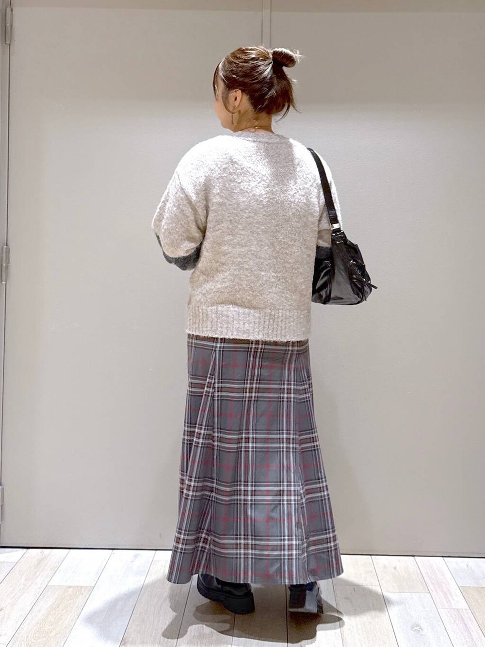 グレー系のスカート、ブラック系のブーツ、ブラック系のショルダーバッグを着用したレディースの冬コーディネートの3枚目の写真