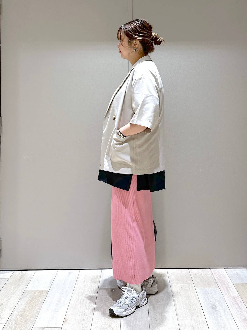 ブラック系のショルダーバッグ、ベージュ系のテーラードジャケット、ピンク系のスカートを着用したレディースの春コーディネートの2枚目の写真