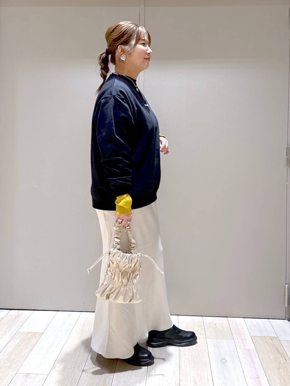 ブラック系のニット/セーター、ホワイト系のスカート、ブラック系のブーツを着用したレディースの冬コーディネートの2枚目の写真