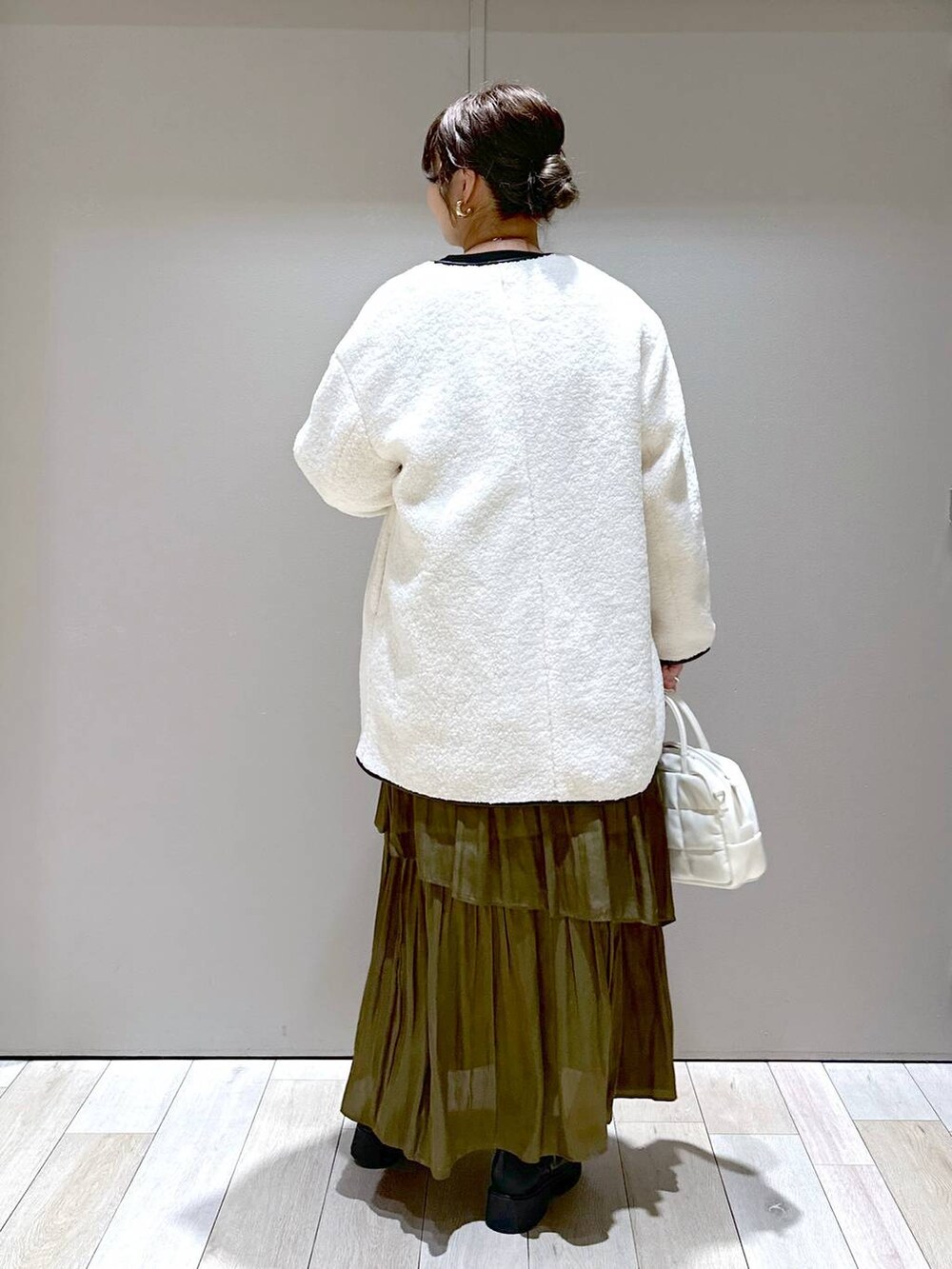 ホワイト系のボストンバッグ、ホワイト系のその他アウター、ブラック系のブーツを着用したレディースの秋コーディネートの3枚目の写真