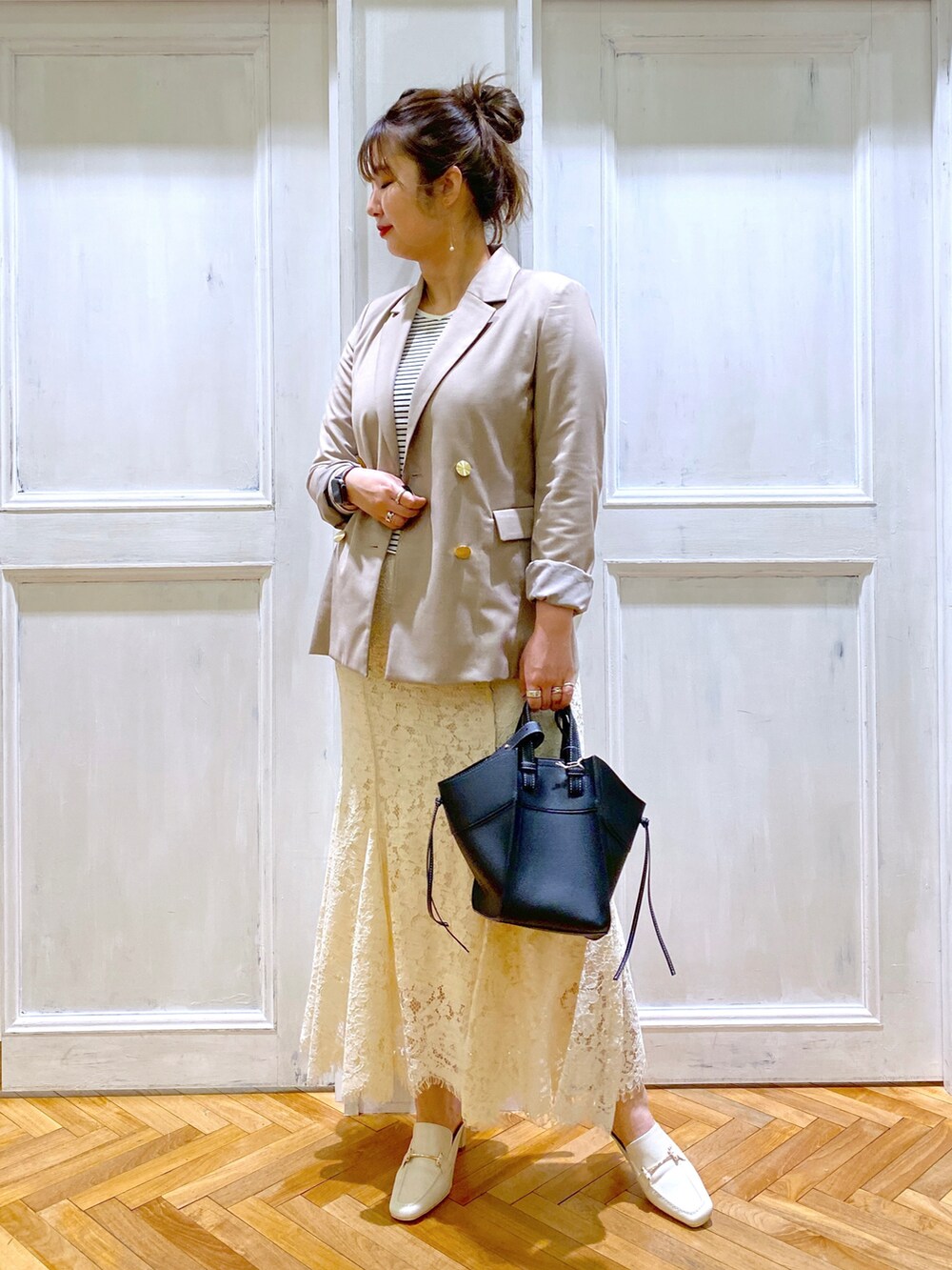 ベージュ系のテーラードジャケット、ホワイト系のスカート、ホワイト系のサンダルを着用したレディースの春コーディネートの4枚目の写真