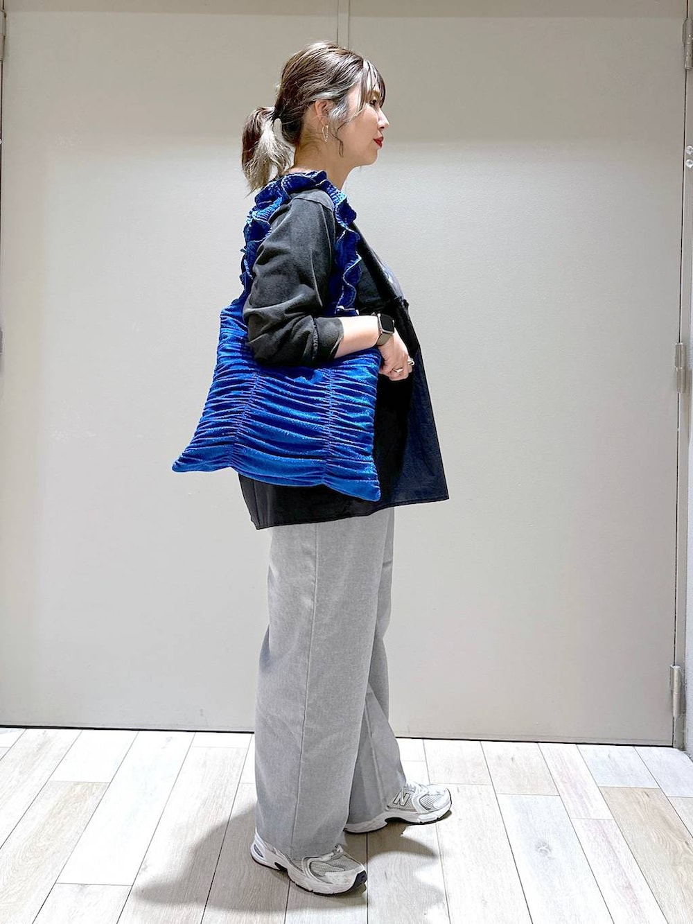 ブルー系のトートバッグ、グレー系のスラックス、グレー系のTシャツ/カットソーを着用したレディースの冬コーディネートの2枚目の写真