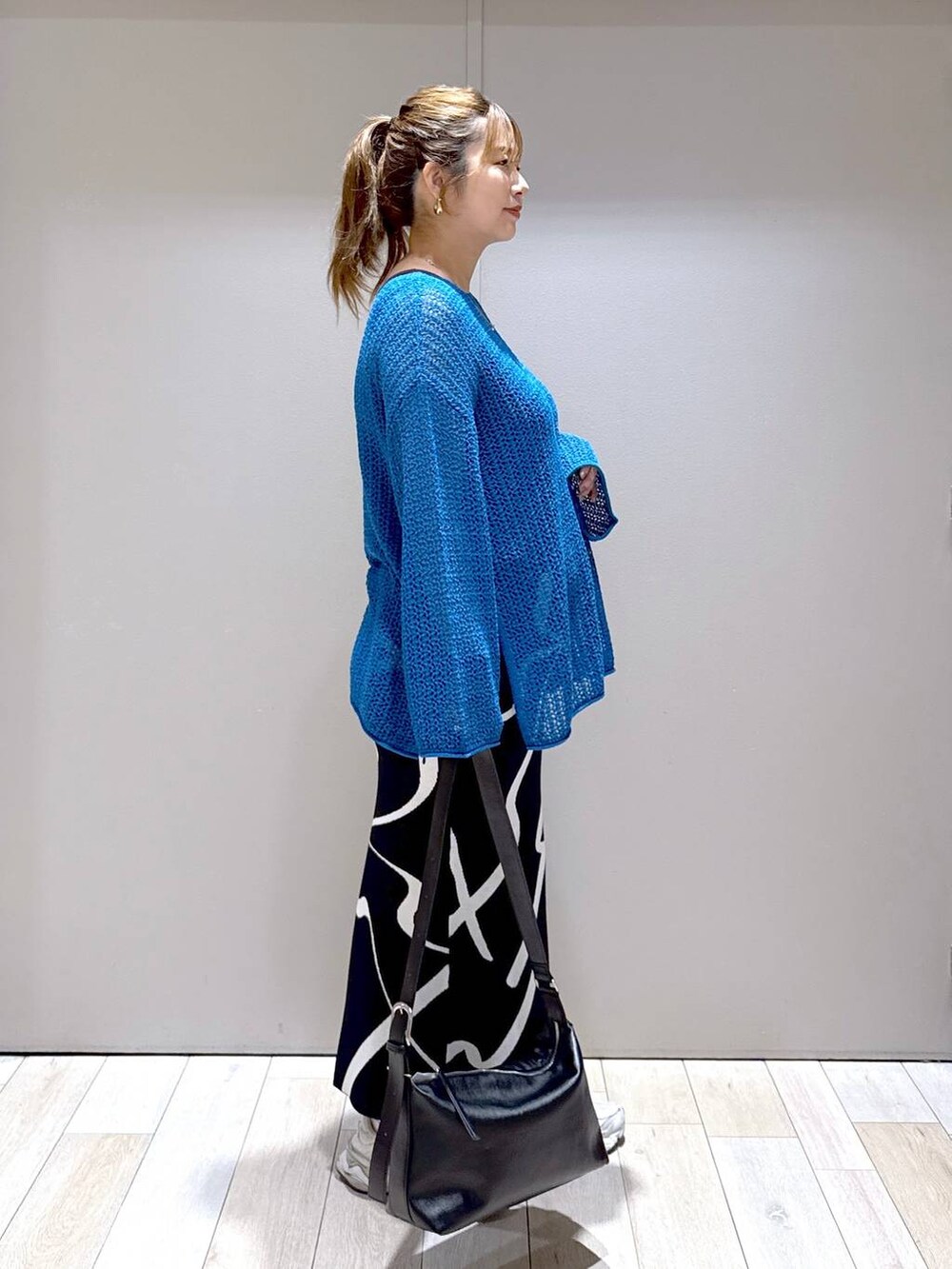 ブラック系のスカート、ブルー系のニット/セーター、ブラック系のショルダーバッグを着用したレディースの秋コーディネートの2枚目の写真