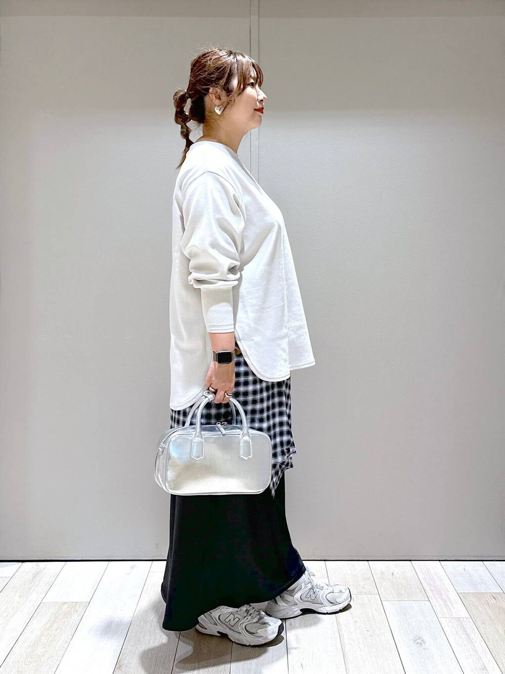 ベージュ系のTシャツ/カットソー、シルバー系のボストンバッグ、ブラック系のスカートを着用したレディースの秋コーディネートの3枚目の写真