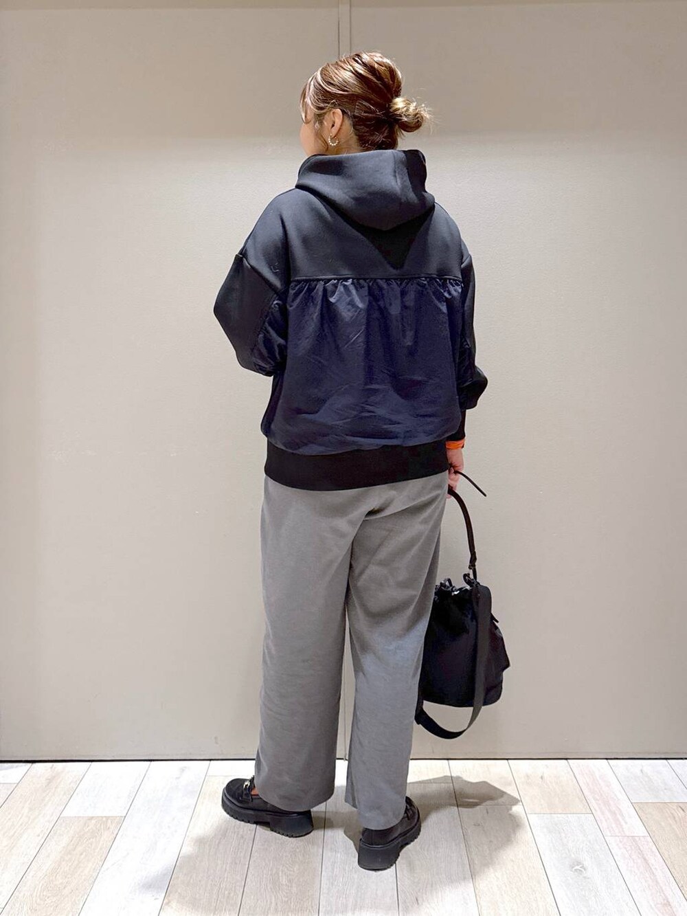 ブラック系のショルダーバッグ、ブラック系のパーカー、オレンジ系のTシャツ/カットソーを着用したレディースの冬コーディネートの3枚目の写真