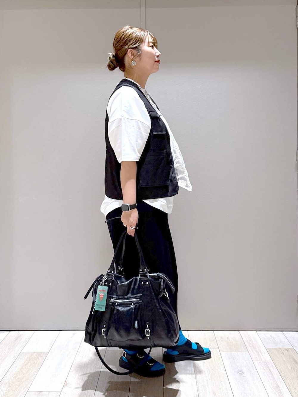 ブラック系のスカート、ブラック系のトートバッグ、ホワイト系のTシャツ/カットソーを着用したレディースの春コーディネートの2枚目の写真