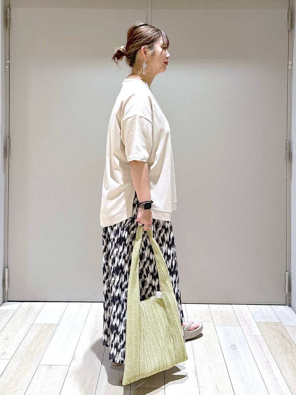 ゴールド系のショルダーバッグ、ブラック系のスカート、ベージュ系のTシャツ/カットソーを着用したレディースの春コーディネートの2枚目の写真