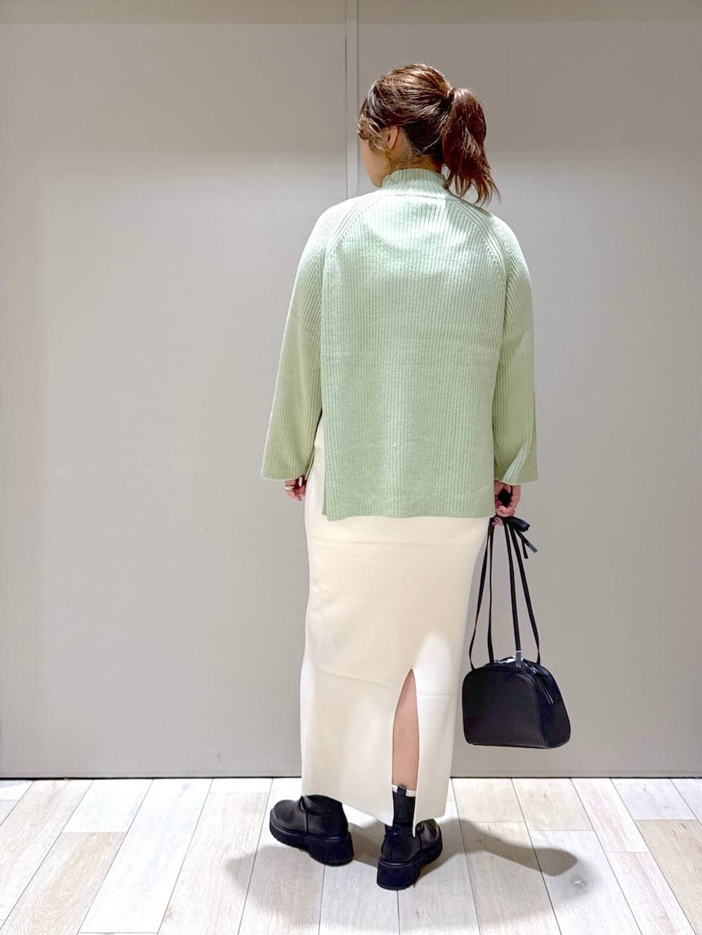 ブラック系のスカート、ブラック系のブーツ、ホワイト系のニット/セーターを着用したレディースの冬コーディネートの3枚目の写真