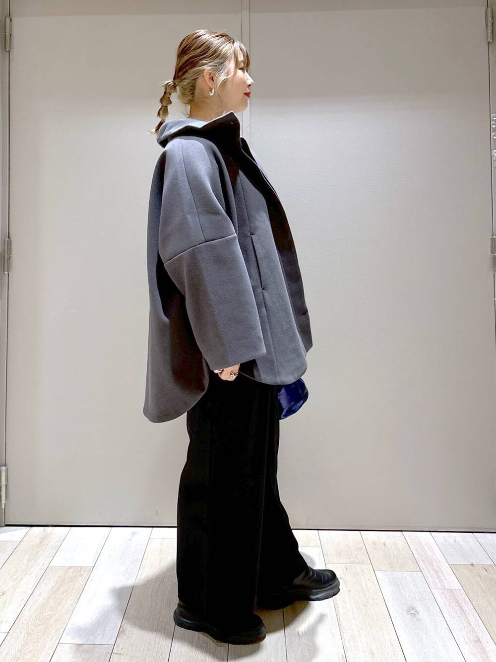 グレー系のポンチョ、ブラック系のその他パンツ、ブラック系のブーツを着用したレディースの冬コーディネートの2枚目の写真