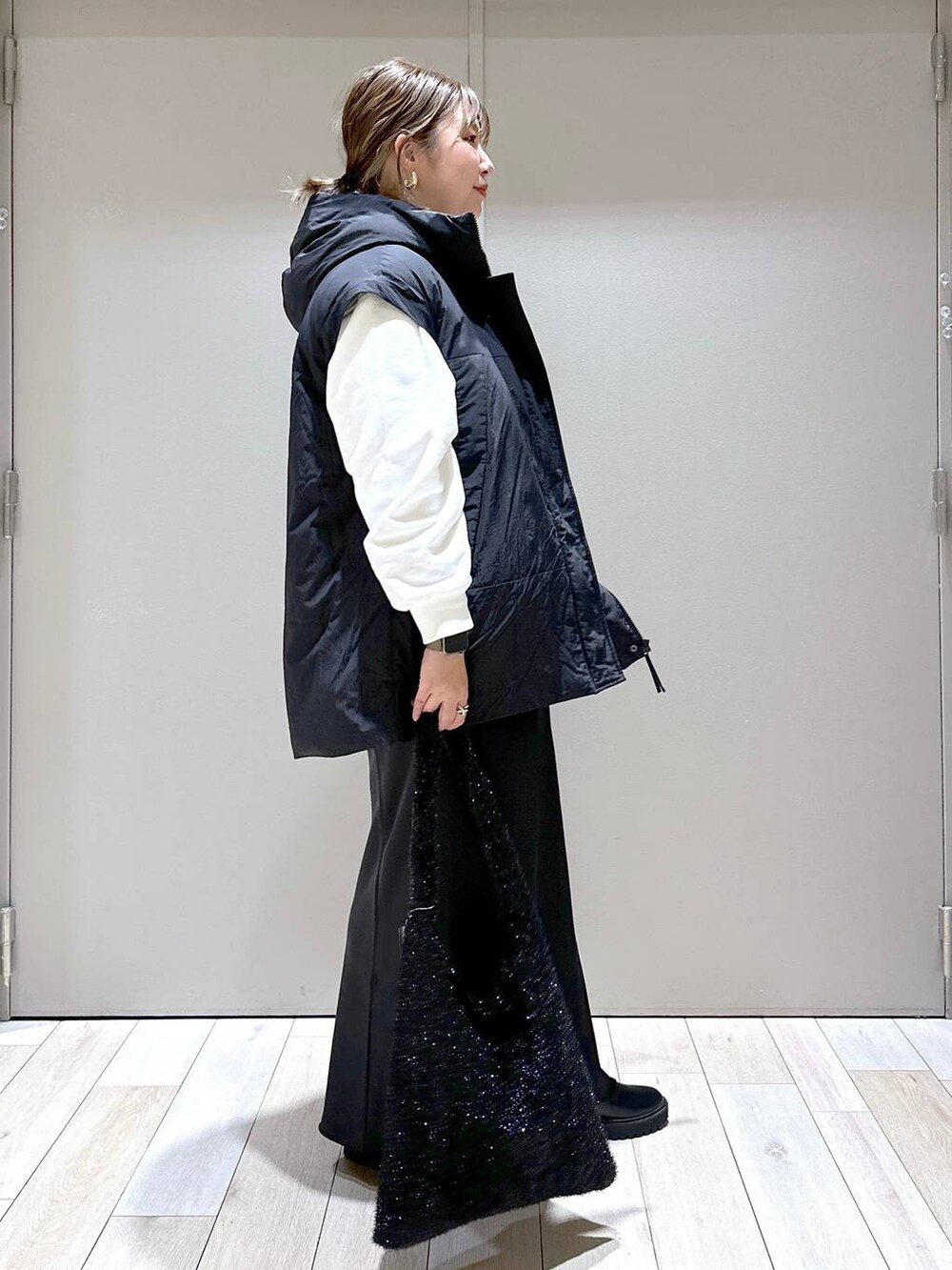 ブラック系のその他アウター、ブラック系のブーツ、ブラック系のショルダーバッグを着用したレディースの秋コーディネートの2枚目の写真