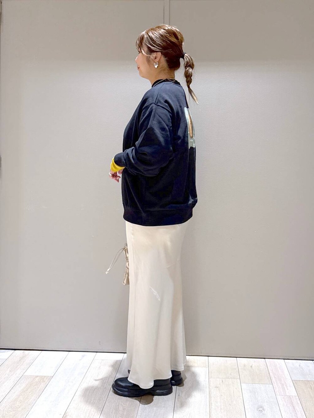 ブラック系のニット/セーター、ホワイト系のスカート、ブラック系のブーツを着用したレディースの冬コーディネートの4枚目の写真