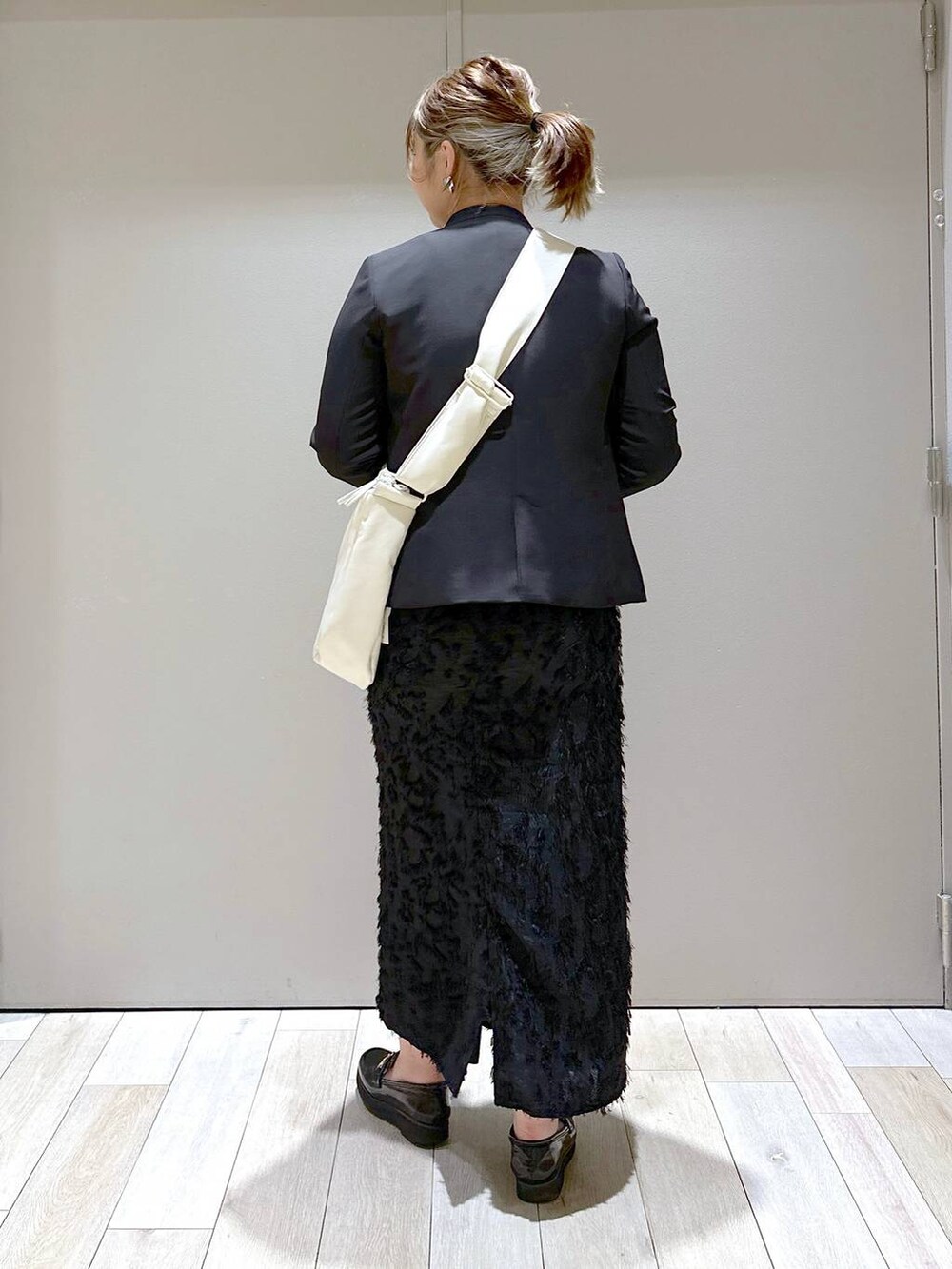 ブラック系のスカート、ホワイト系のショルダーバッグ、グレー系のニット/セーターを着用したレディースの冬コーディネートの3枚目の写真