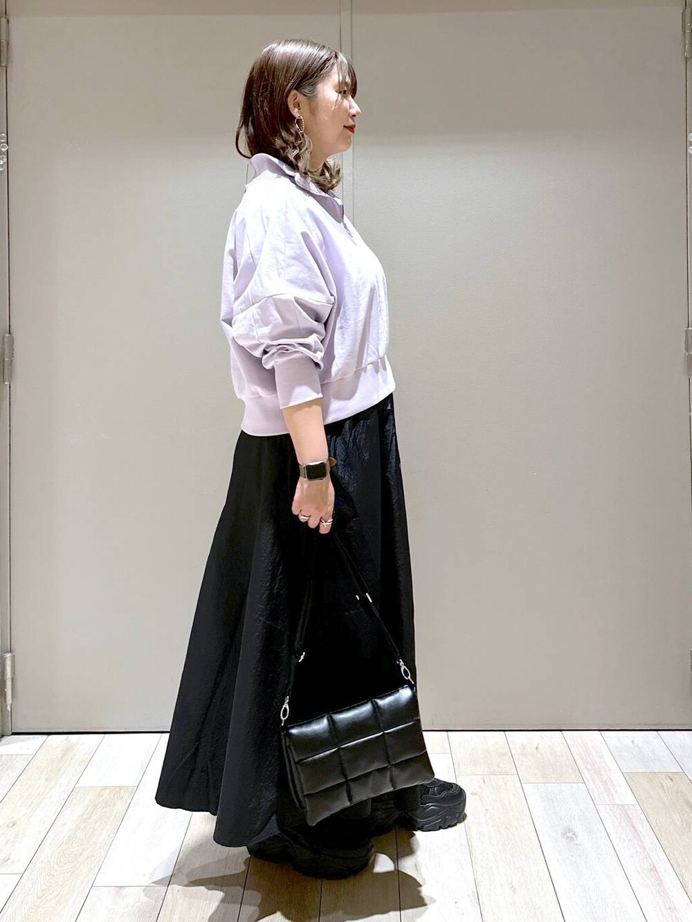 ブラック系のスニーカー、ブラック系のショルダーバッグ、ブラック系のスカートを着用したレディースの春コーディネートの2枚目の写真