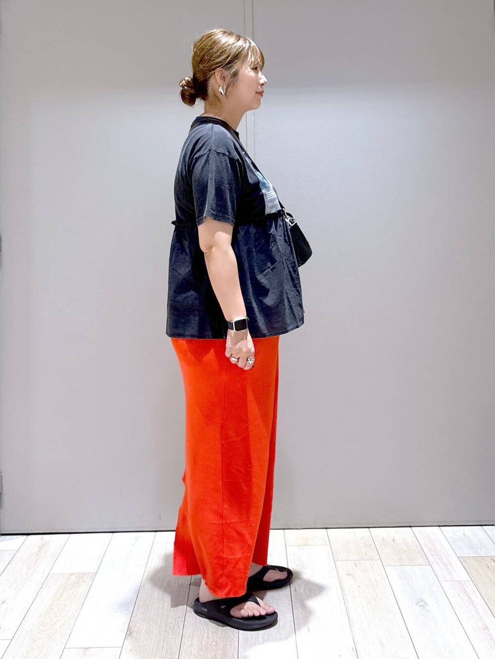 オレンジ系のスカート、ブラック系のTシャツ/カットソー、ブラック系のショルダーバッグを着用したレディースの夏コーディネートの2枚目の写真