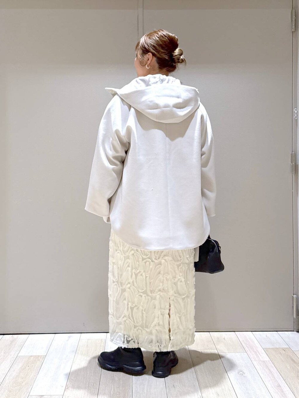 ホワイト系のポンチョ、ブラック系のブーツ、ピンク系のスウェットを着用したレディースの冬コーディネートの4枚目の写真