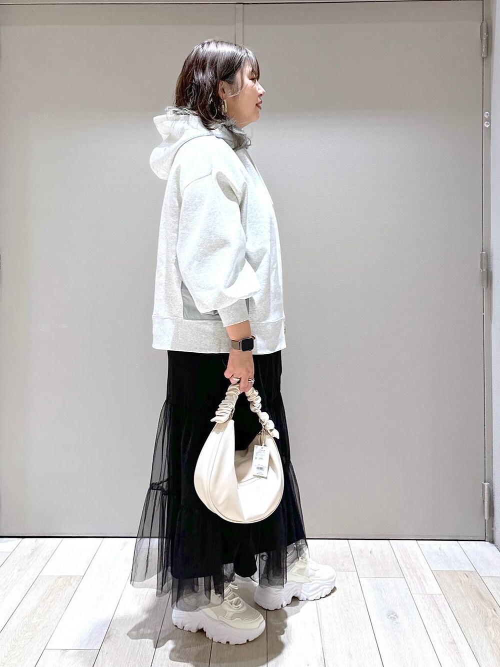 ホワイト系のスニーカー、グレー系のパーカー、ホワイト系のショルダーバッグを着用したレディースの冬コーディネートの2枚目の写真