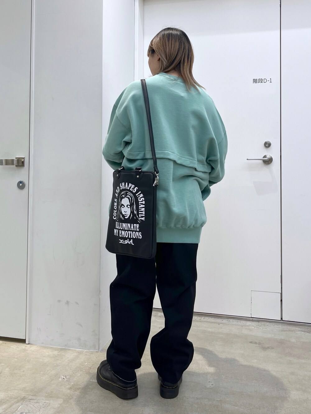 グリーン系のワンピース、ブラック系のデニムパンツ、ブラック系のショルダーバッグを着用したレディースの冬コーディネートの2枚目の写真