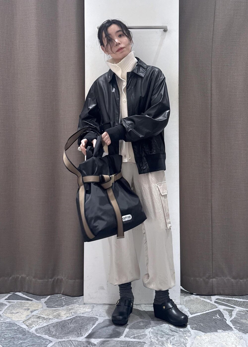 ホワイト系のカーゴパンツ、ブラック系のブルゾン、ホワイト系のカーディガン/ボレロを着用したレディースの冬コーディネートの3枚目の写真