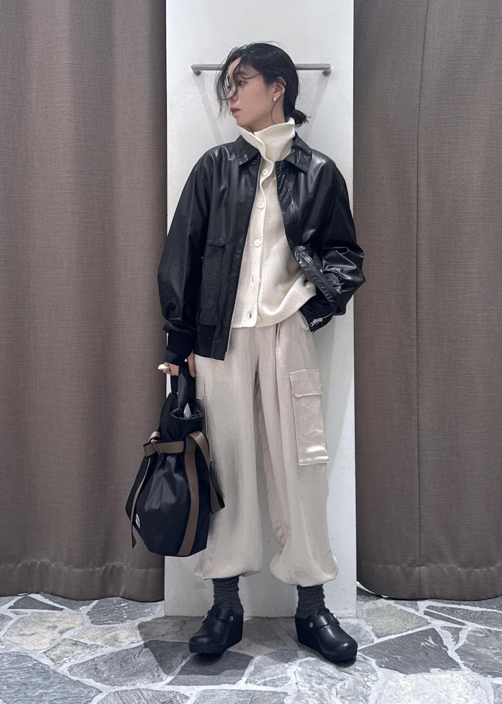 ホワイト系のカーゴパンツ、ブラック系のブルゾン、ホワイト系のカーディガン/ボレロを着用したレディースの冬コーディネートの2枚目の写真