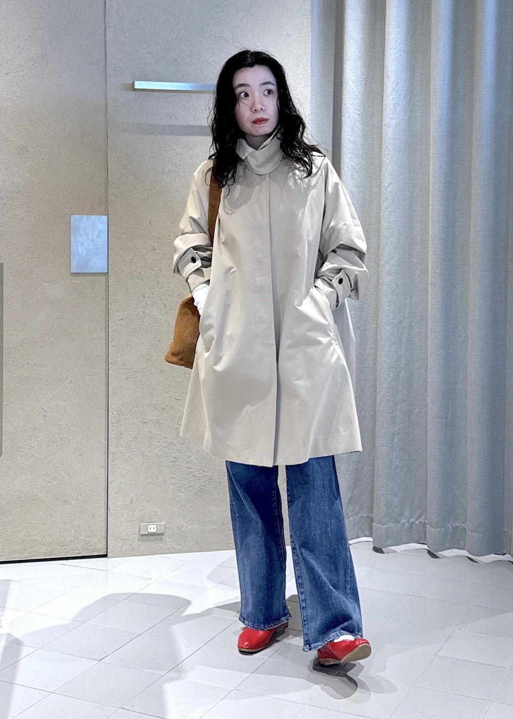 ブルー系のデニムパンツ、ホワイト系のTシャツ/カットソー、ベージュ系のステンカラーコートを着用したレディースの冬コーディネートの3枚目の写真