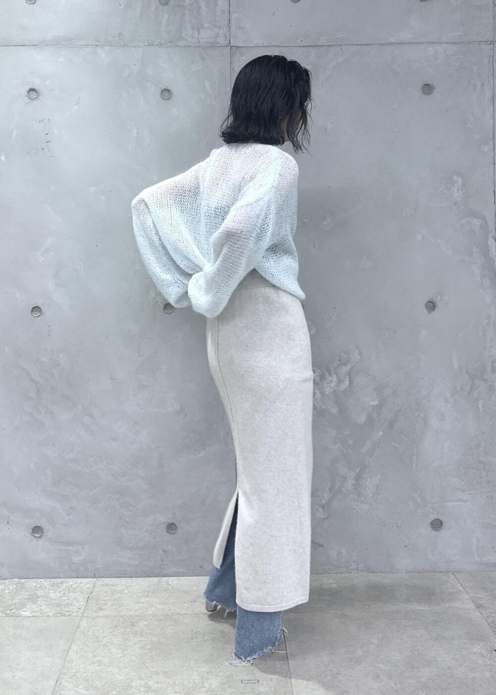 ホワイト系のスカート、ブルー系のニット/セーター、ブルー系のデニムパンツを着用したレディースの秋コーディネートの4枚目の写真