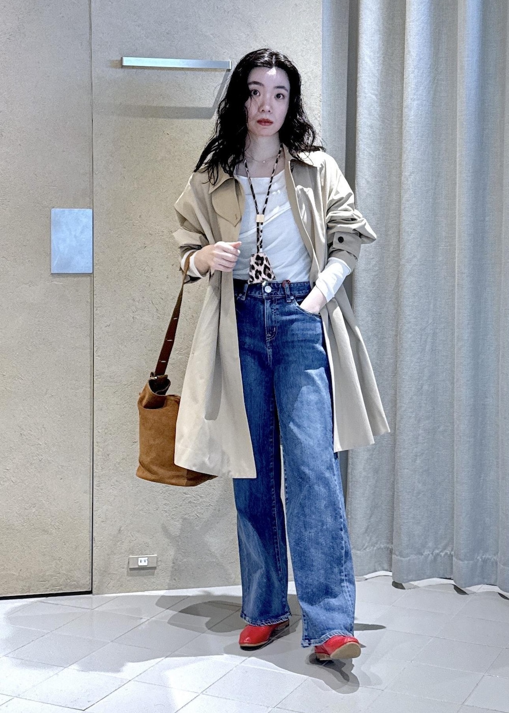 ブルー系のデニムパンツ、ホワイト系のTシャツ/カットソー、ベージュ系のステンカラーコートを着用したレディースの冬コーディネートの2枚目の写真