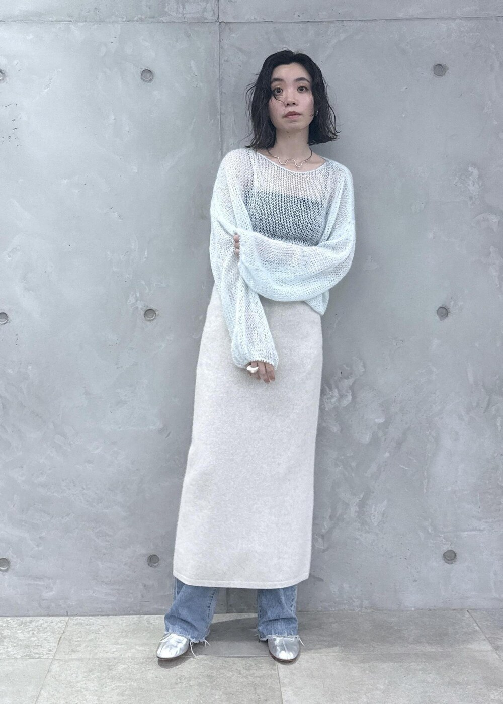 ホワイト系のスカート、ブルー系のニット/セーター、ブルー系のデニムパンツを着用したレディースの秋コーディネートの2枚目の写真