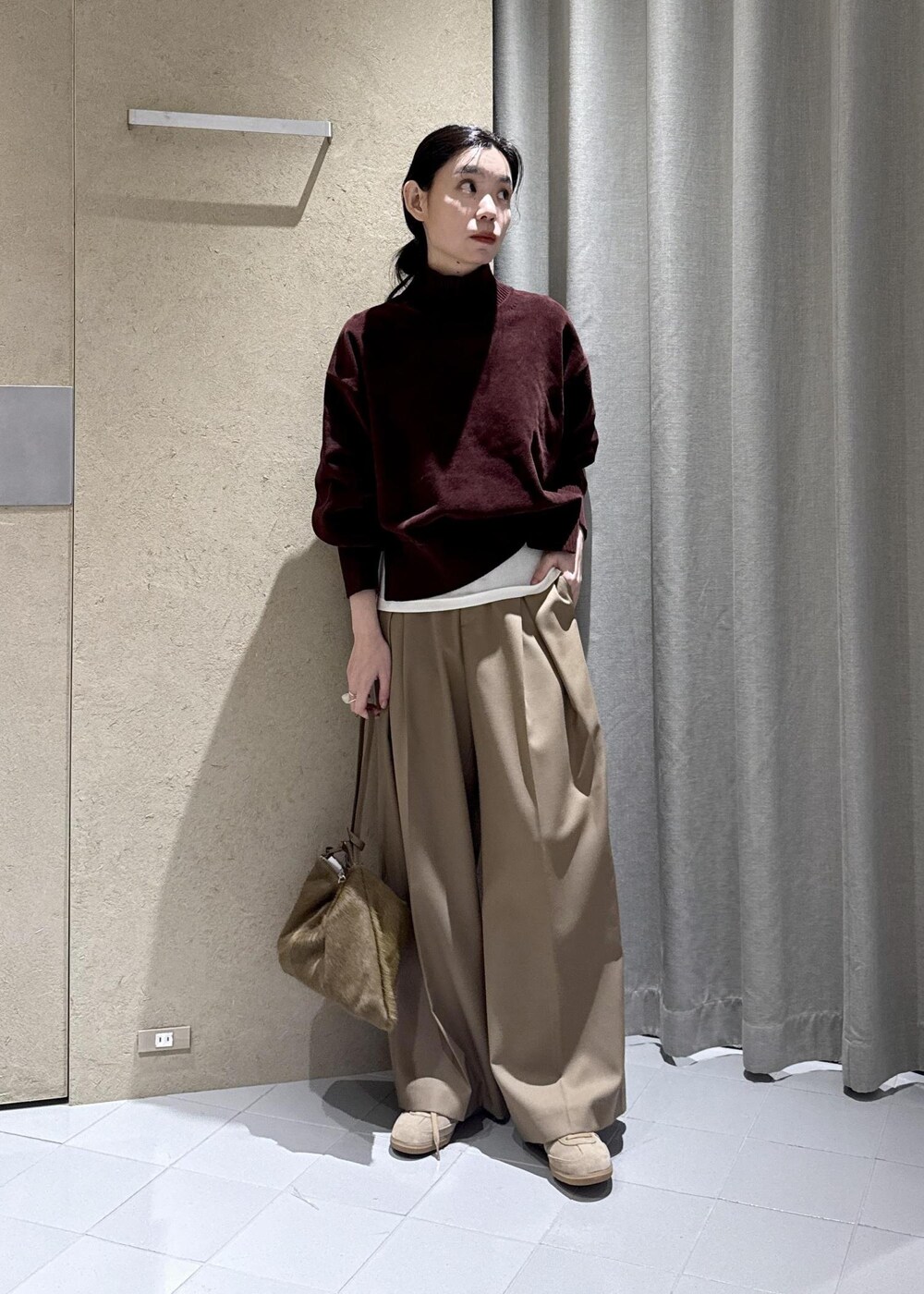 ホワイト系のTシャツ/カットソー、ベージュ系のスラックス、ブラウン系のショルダーバッグを着用したレディースの秋コーディネートの2枚目の写真