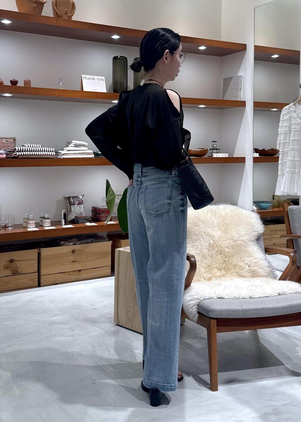 ブラック系のかごバッグ、ブラック系のサンダル、ブルー系のデニムパンツを着用したレディースの春コーディネートの2枚目の写真