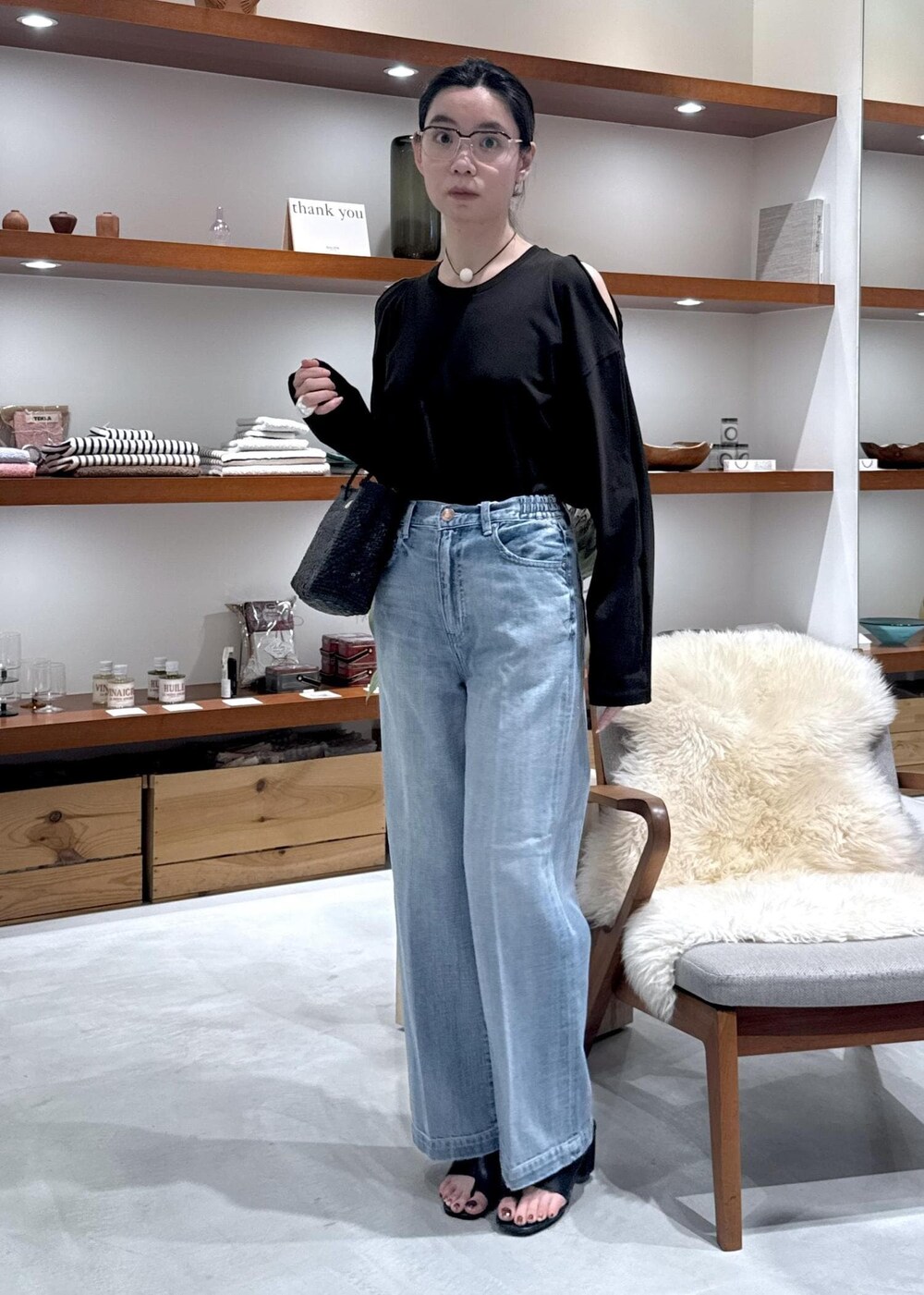 ブラック系のかごバッグ、ブラック系のサンダル、ブルー系のデニムパンツを着用したレディースの春コーディネートの6枚目の写真