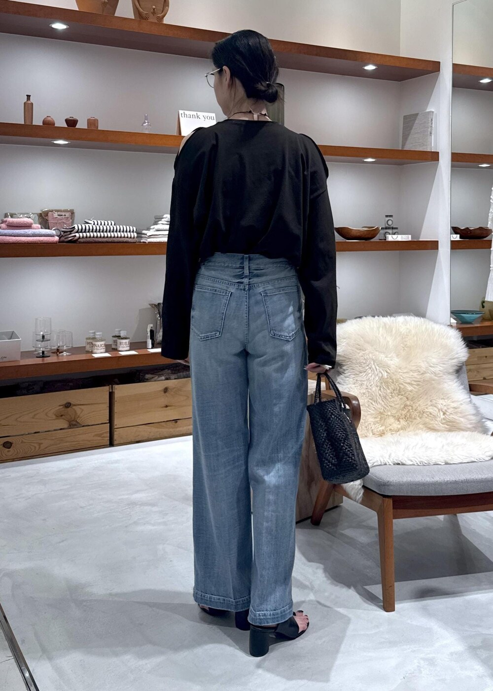 ブラック系のかごバッグ、ブラック系のサンダル、ブルー系のデニムパンツを着用したレディースの春コーディネートの5枚目の写真