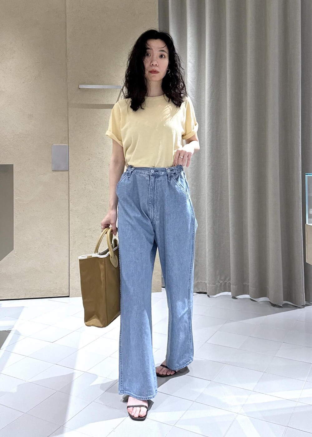 ホワイト系のTシャツ/カットソー、ブルー系のデニムパンツ、ベージュ系のトートバッグを着用したレディースの夏コーディネートの2枚目の写真