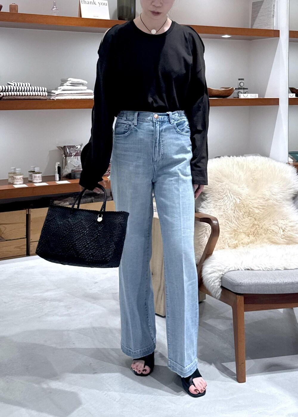 ブラック系のかごバッグ、ブラック系のサンダル、ブルー系のデニムパンツを着用したレディースの春コーディネートの7枚目の写真