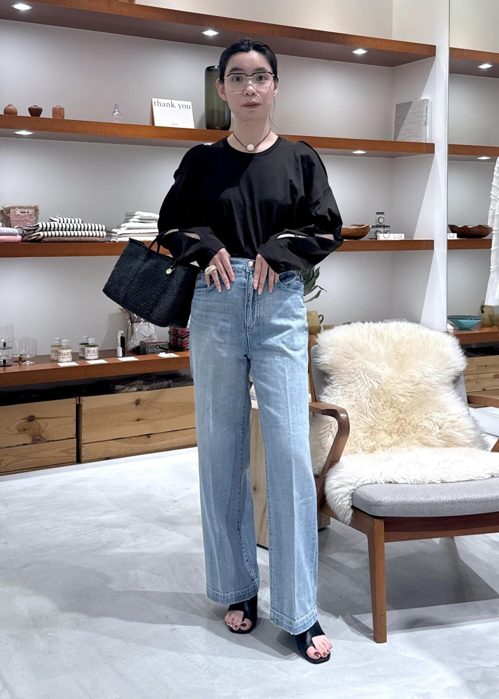 ブラック系のかごバッグ、ブラック系のサンダル、ブルー系のデニムパンツを着用したレディースの春コーディネートの3枚目の写真