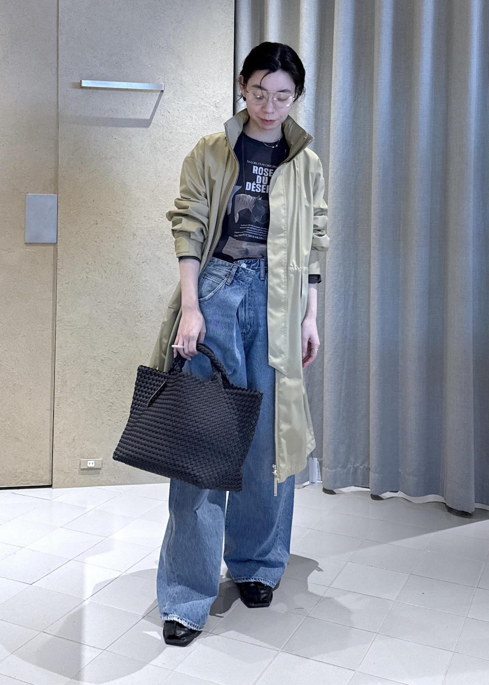 ベージュ系のミリタリージャケット、グレー系のTシャツ/カットソー、ブラック系のトートバッグを着用したレディースの春コーディネートの2枚目の写真