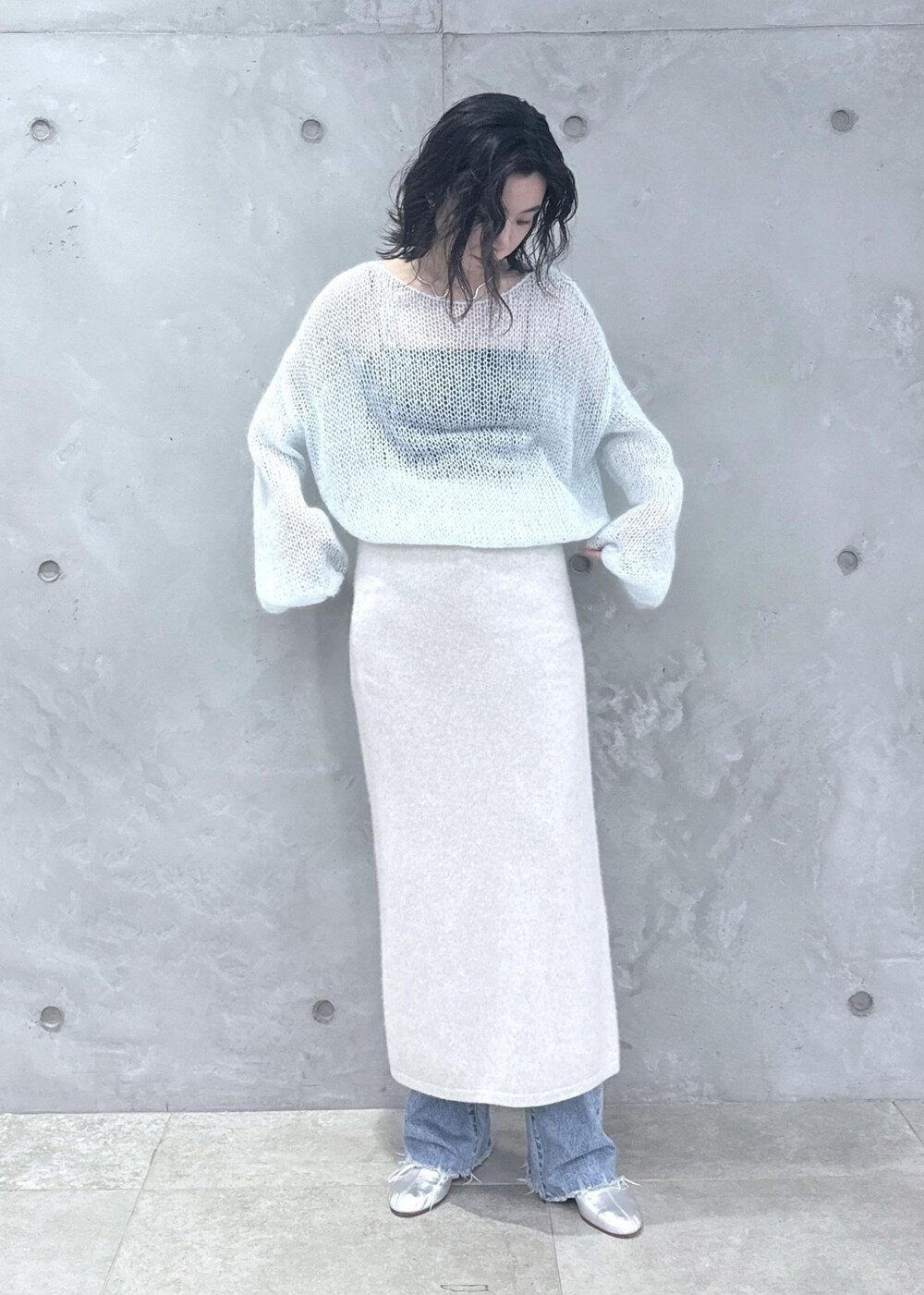 ホワイト系のスカート、ブルー系のニット/セーター、ブルー系のデニムパンツを着用したレディースの秋コーディネートの3枚目の写真