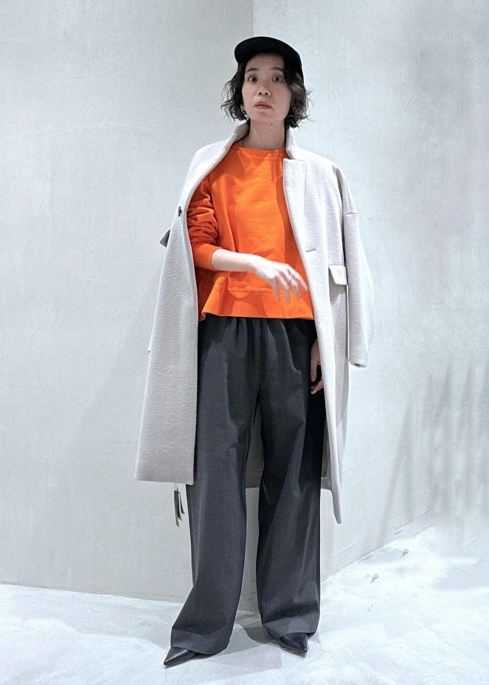 グレー系のチェスターコート、オレンジ系のスウェットを着用したレディースの冬コーディネートの2枚目の写真