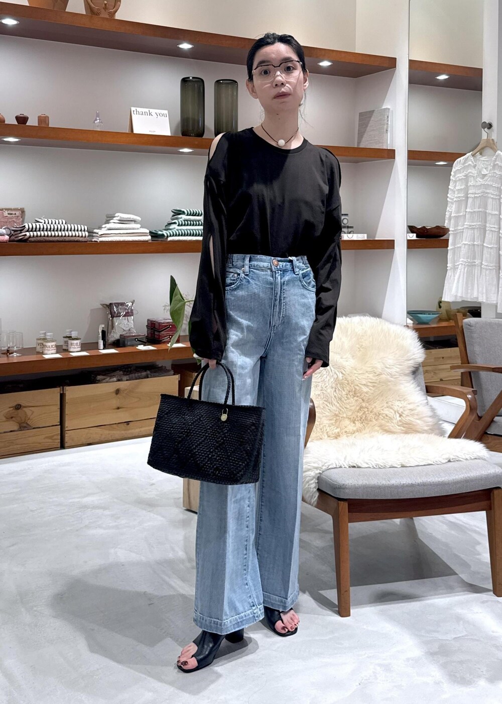 ブラック系のかごバッグ、ブラック系のサンダル、ブルー系のデニムパンツを着用したレディースの春コーディネートの4枚目の写真
