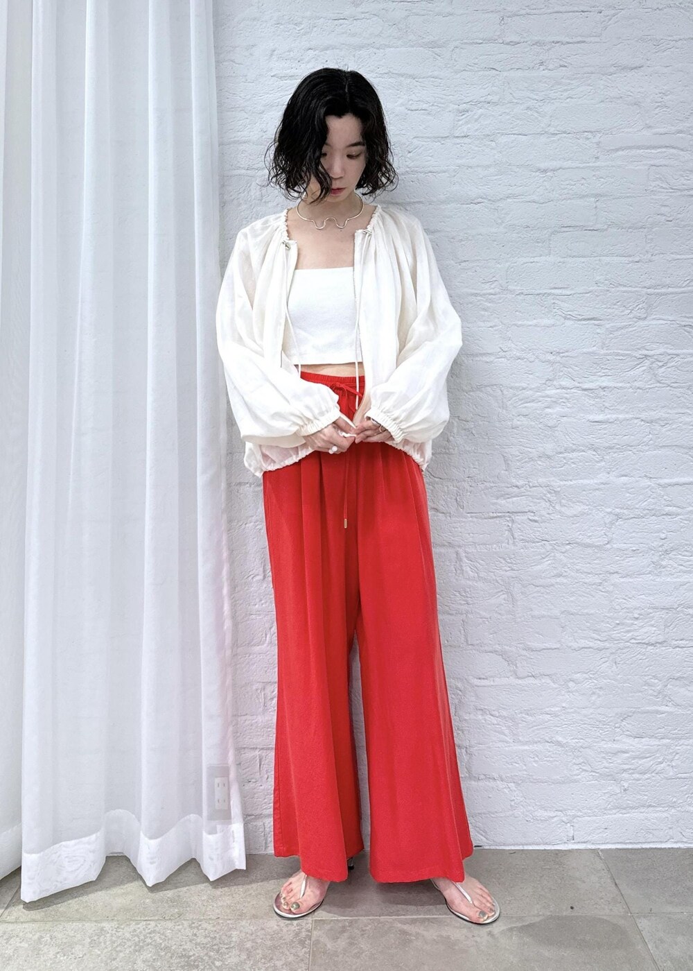 レッド系のその他パンツ、ホワイト系のブルゾンを着用したレディースの春コーディネートの2枚目の写真
