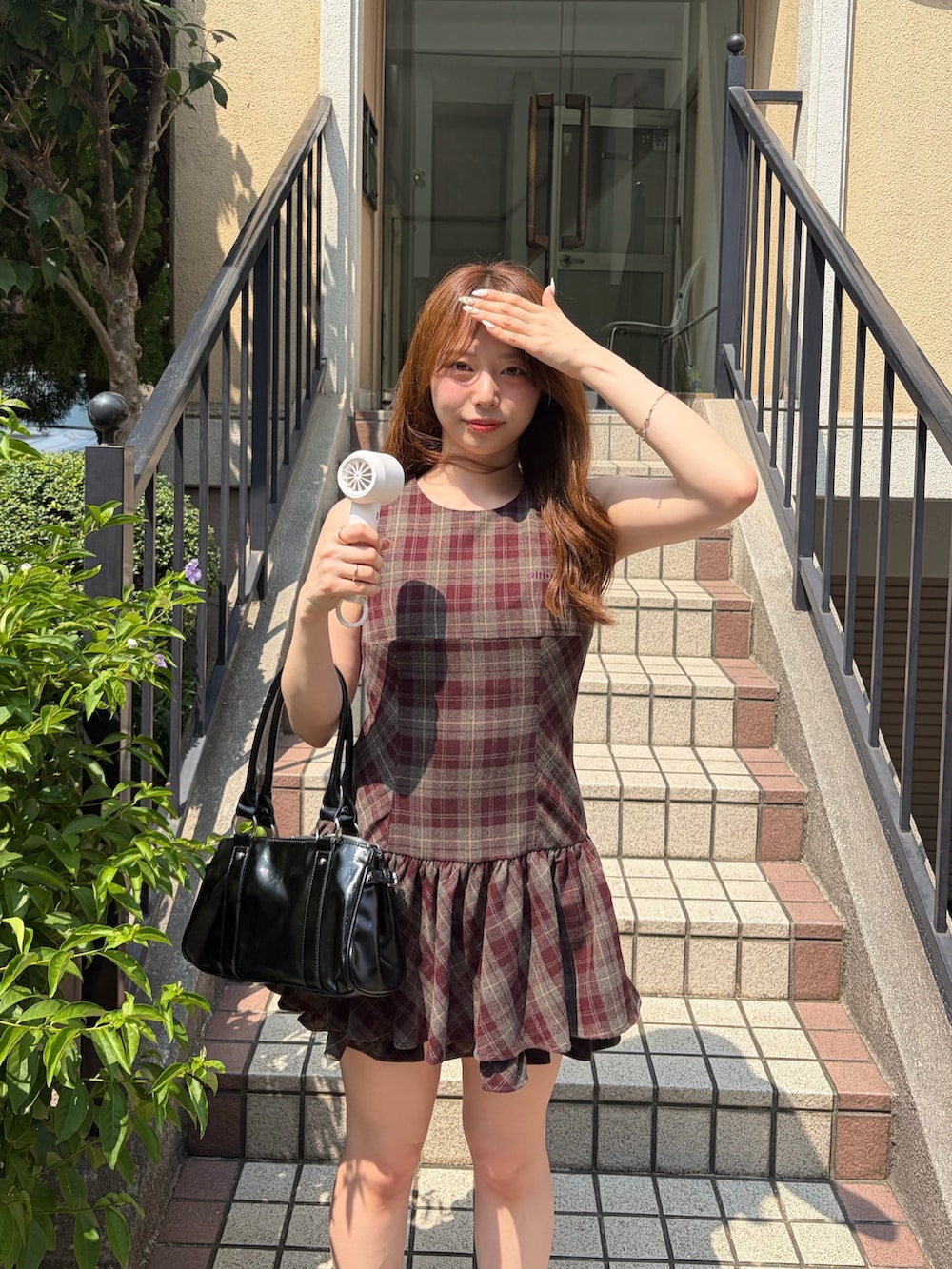 レッド系のワンピース、ブラウン系のブーツ、ブラック系のボストンバッグを着用したレディースの夏コーディネートの2枚目の写真