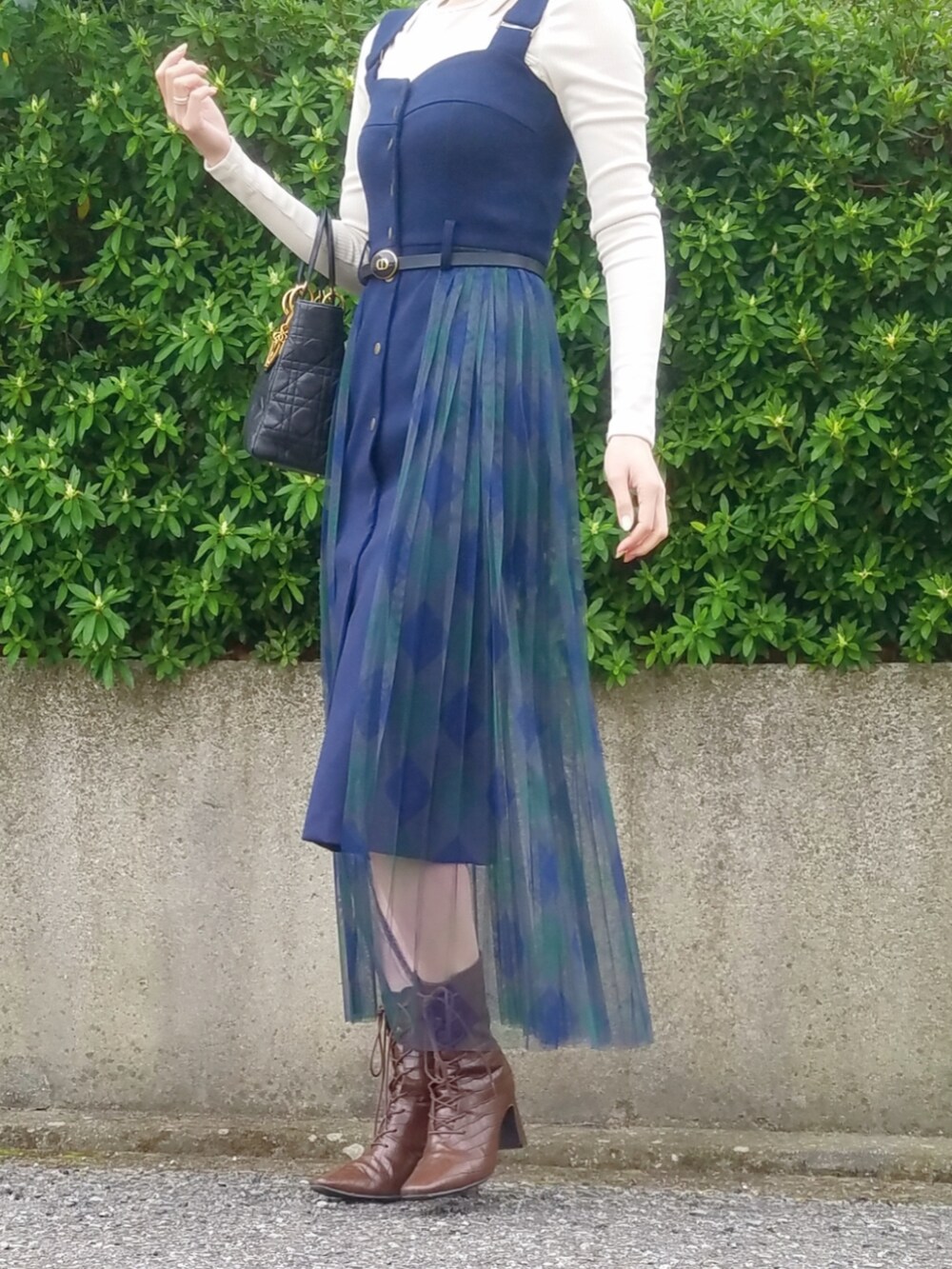 ブラック系のハンドバッグ、ブルー系のワンピース、ブラウン系のブーツを着用したレディースの春コーディネートの2枚目の写真