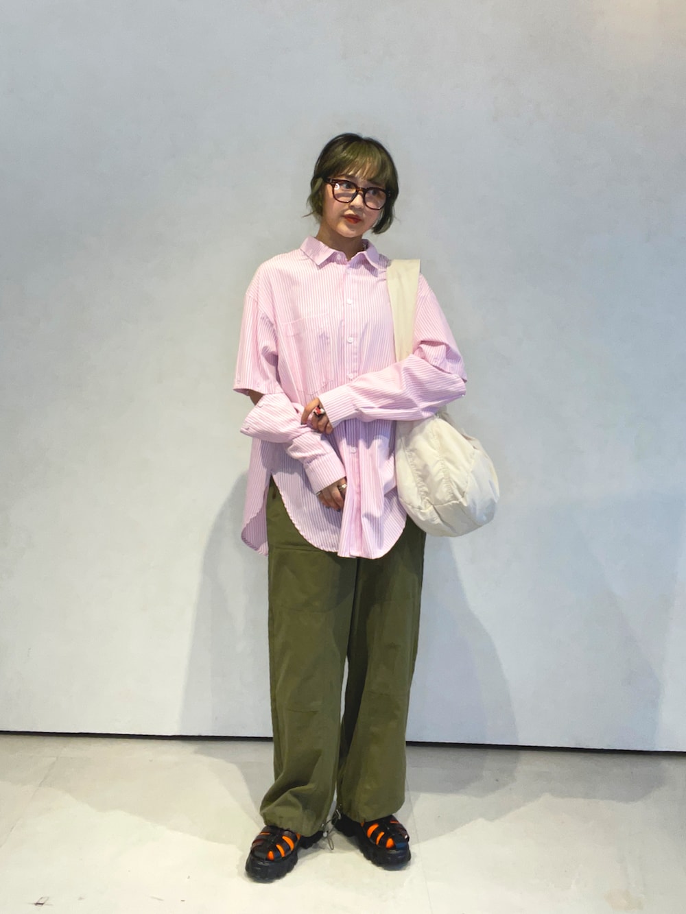 ピンク系のシャツ/ブラウス、グリーン系のカーゴパンツ、ホワイト系のショルダーバッグを着用したレディースの春コーディネートの2枚目の写真