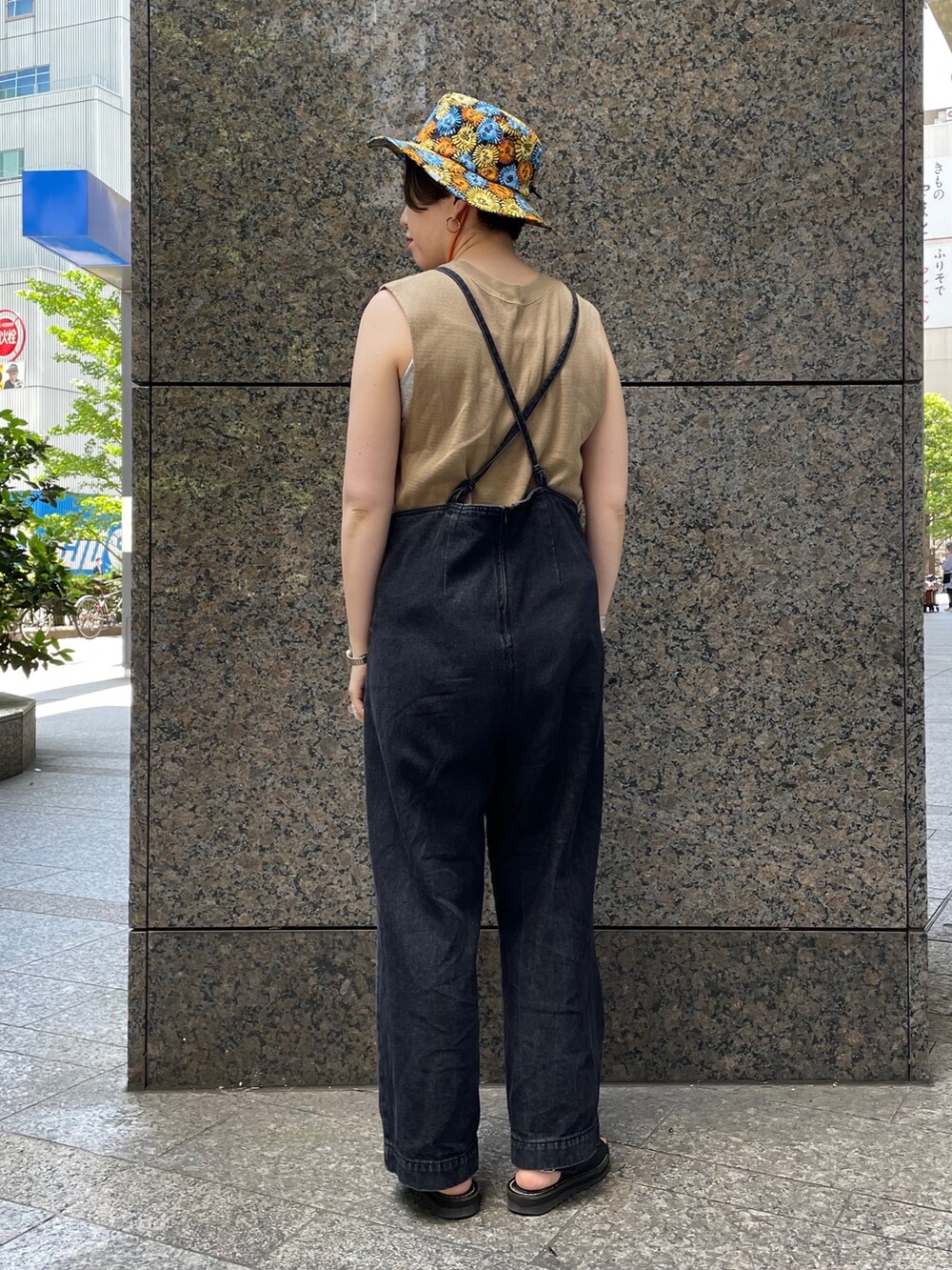 ブラック系のサロペット/オーバーオール、ブラック系のサンダル、オレンジ系のハットを着用したレディースの春コーディネートの2枚目の写真