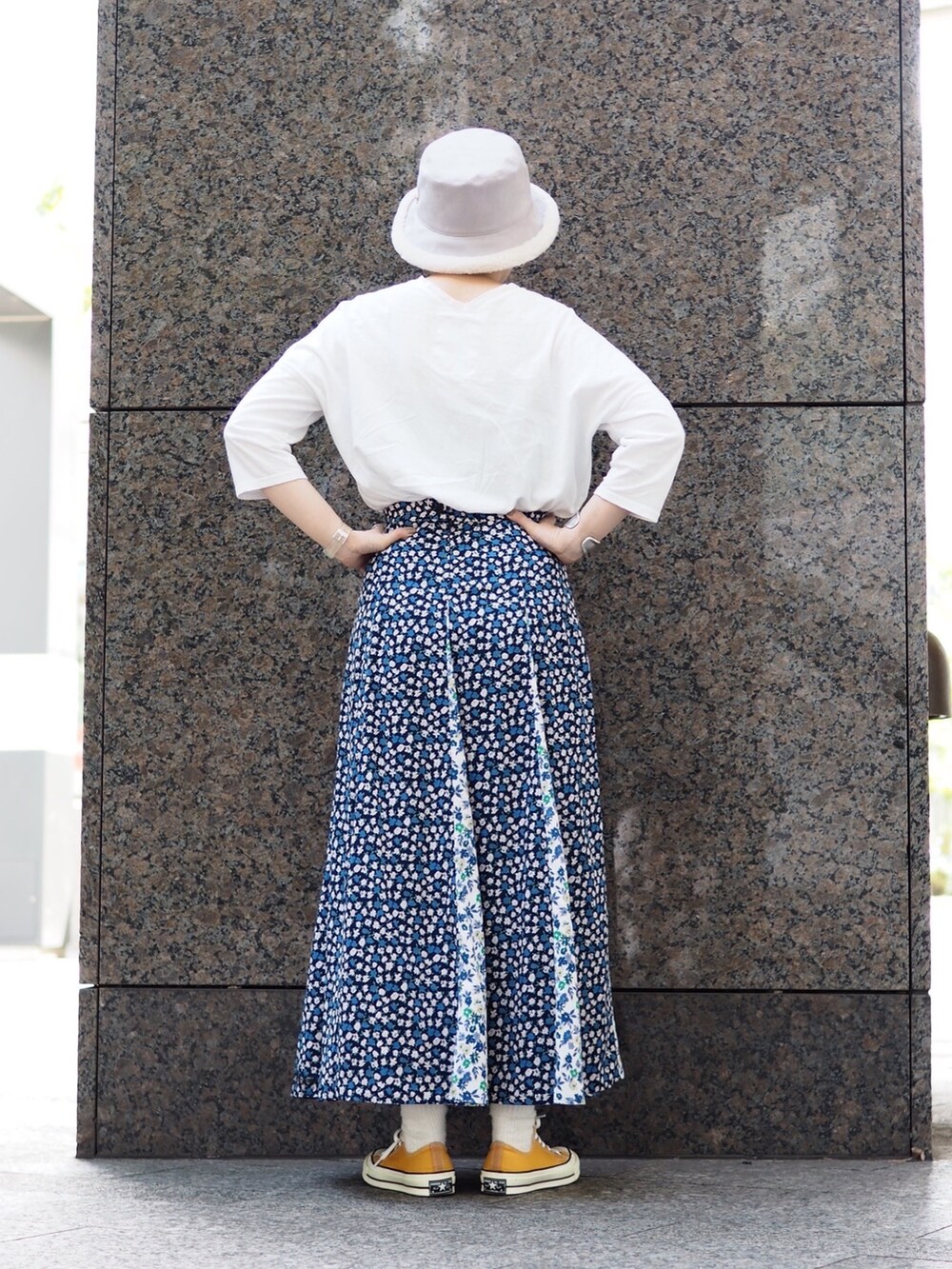 ブルー系のスカート、イエロー系のスニーカー、ベージュ系のハットを着用したレディースの秋コーディネートの2枚目の写真