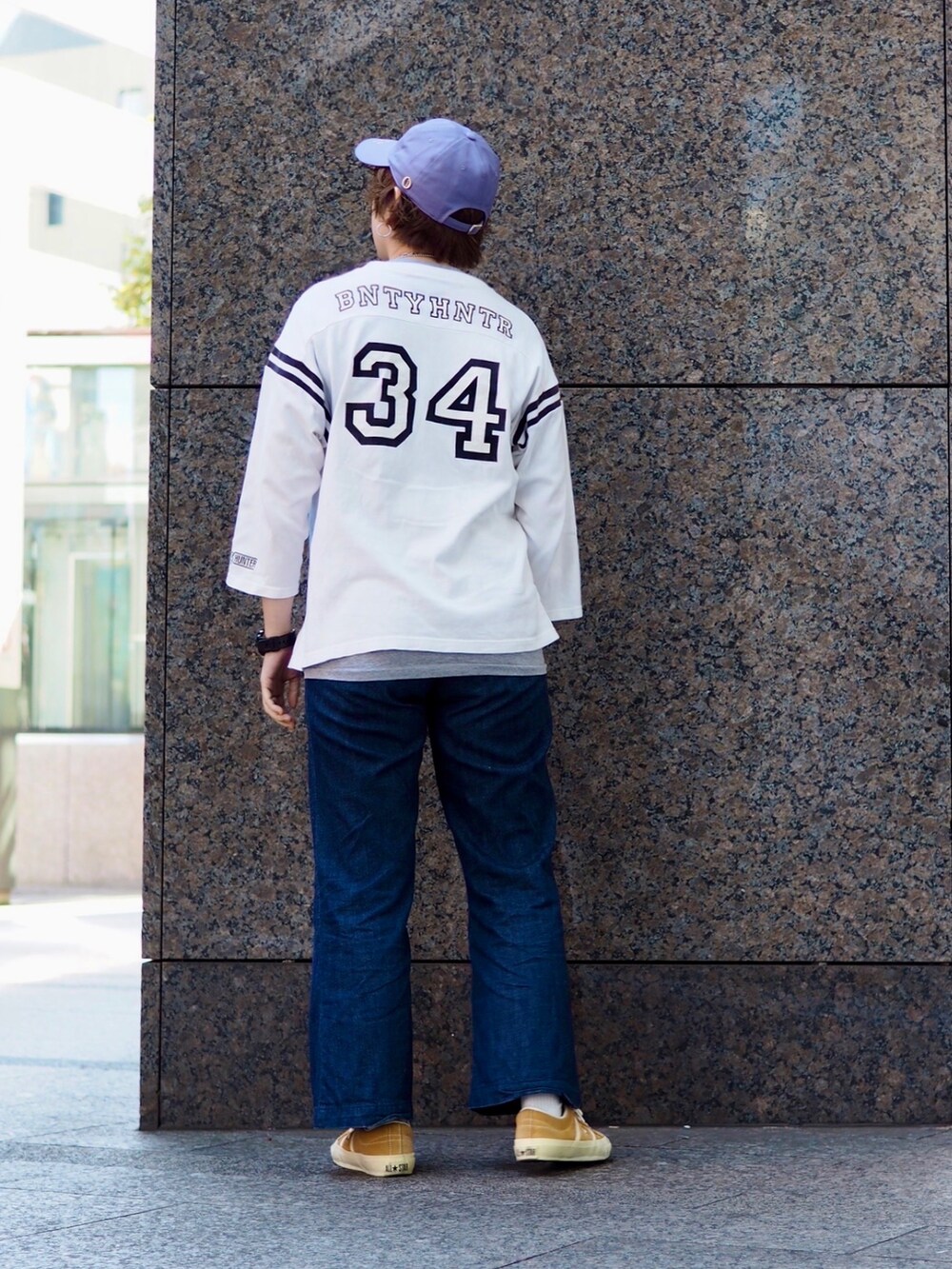 ブルー系のデニムパンツ、イエロー系のスニーカー、パープル系のキャップを着用したレディースの冬コーディネートの2枚目の写真