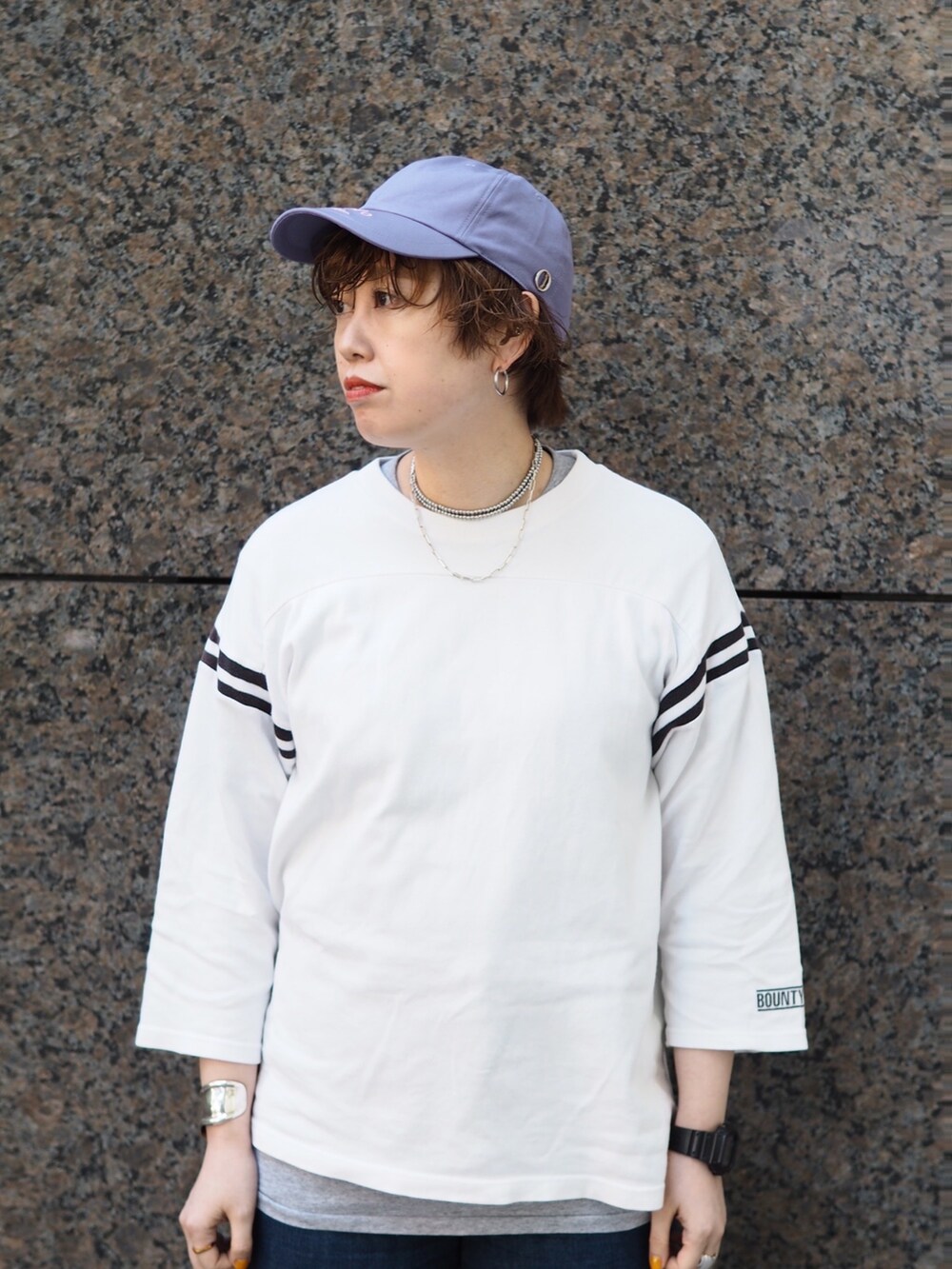 ブルー系のデニムパンツ、イエロー系のスニーカー、パープル系のキャップを着用したレディースの冬コーディネートの3枚目の写真