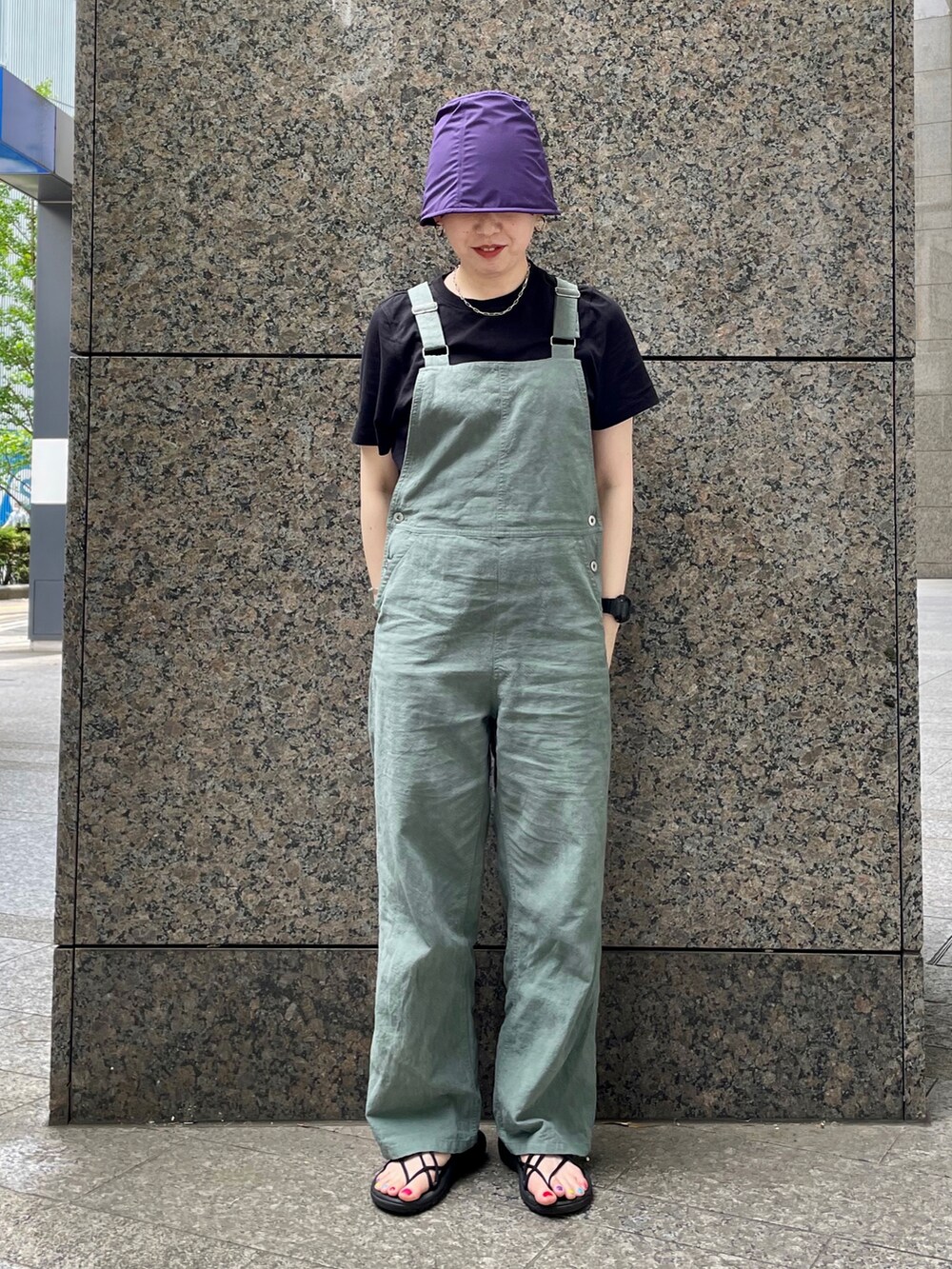 グリーン系のサロペット/オーバーオール、ブラック系のサンダル、パープル系のハットを着用したレディースの春コーディネートの3枚目の写真